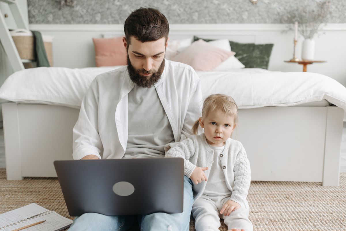 Parent sitting next to baby while working from home; Managing productivity running business